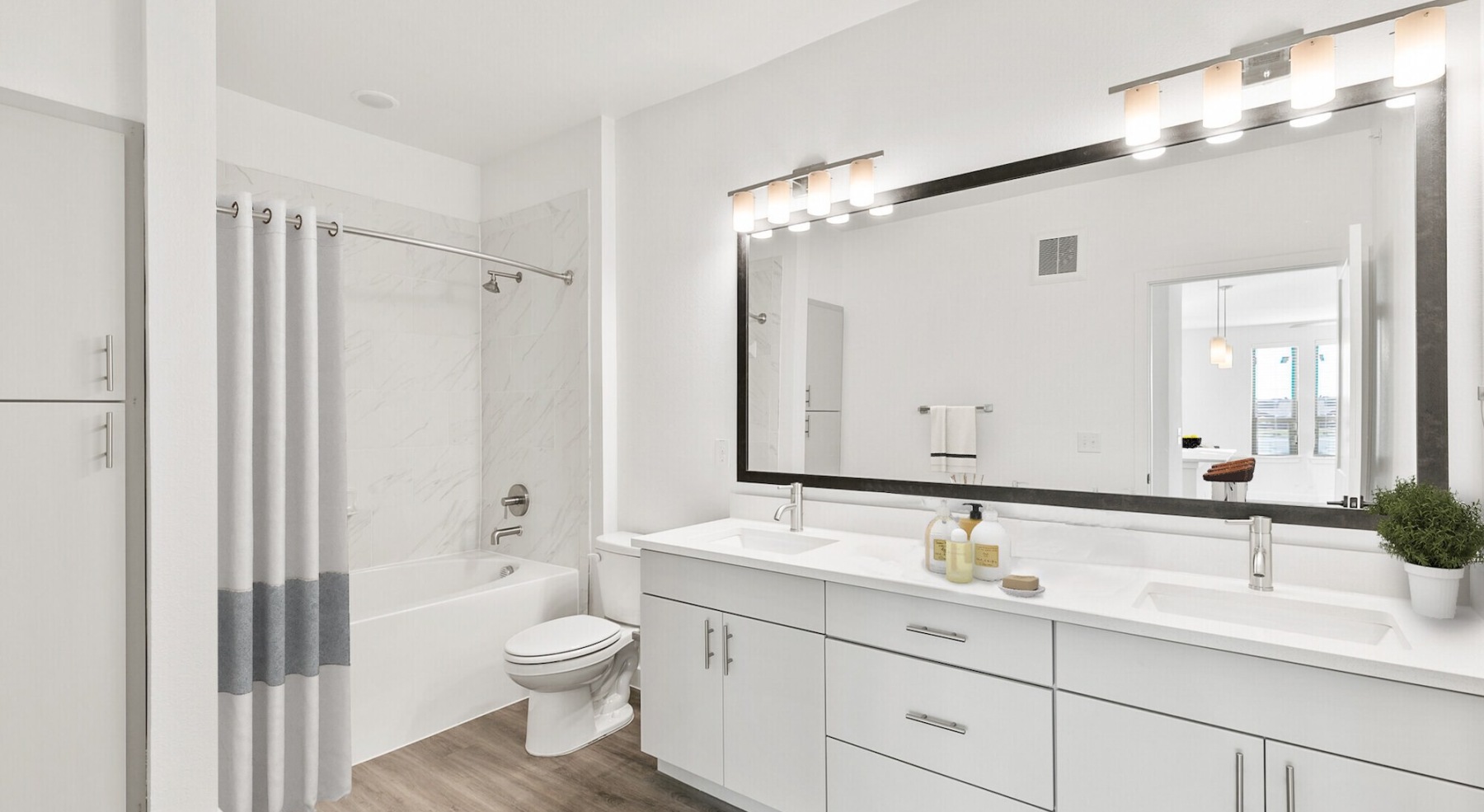 a bathroom with dual white vanity and a large mirror