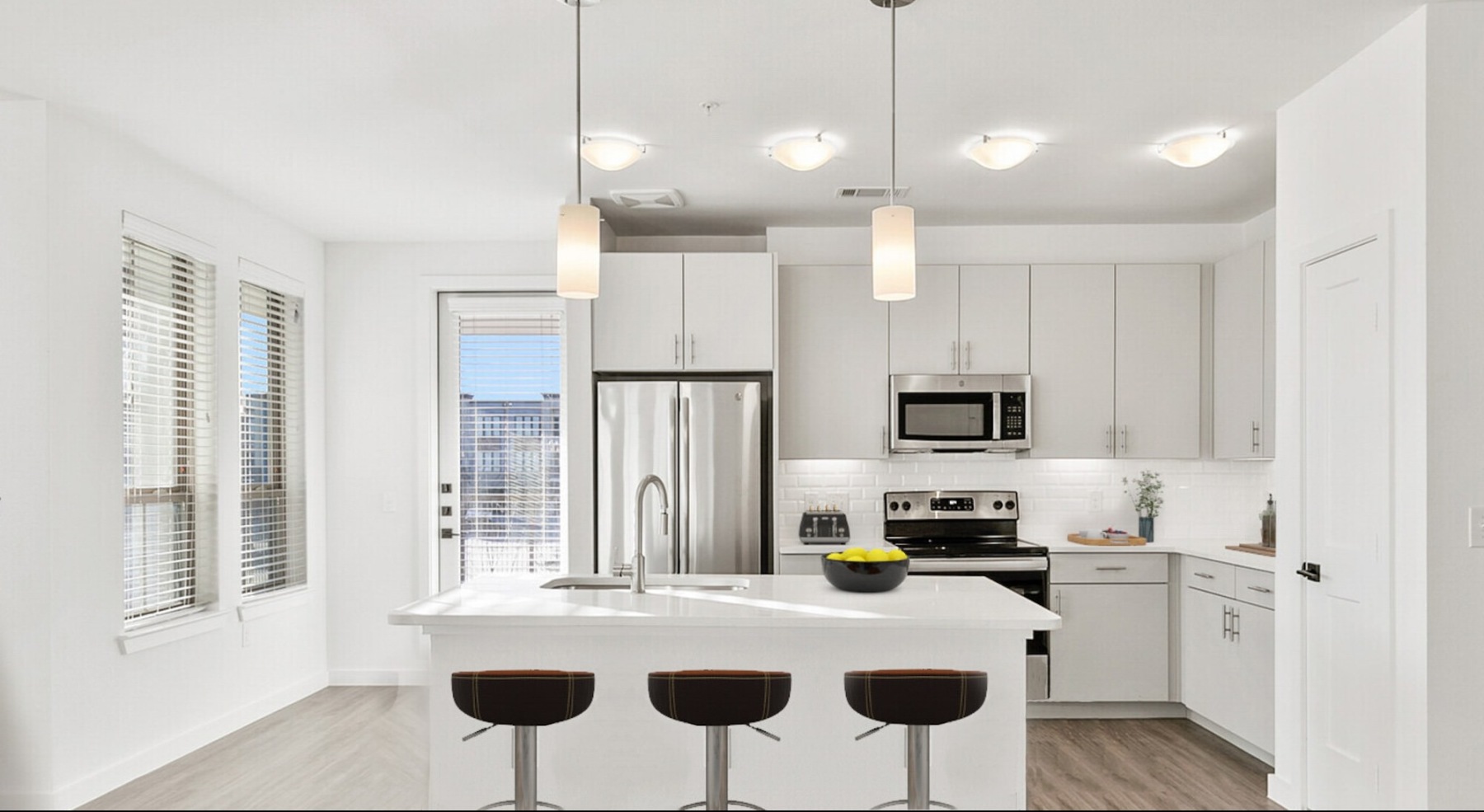 a kitchen with white cabinets and an island with pub seating